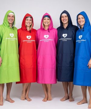 Fem personer står barfodet på række, smilende og iført Mikrofiber Poncho Voksen Mænd/Damer 100x70 cm-perfekt udstyr til vinterbadning- mod en almindelig hvid baggrund.