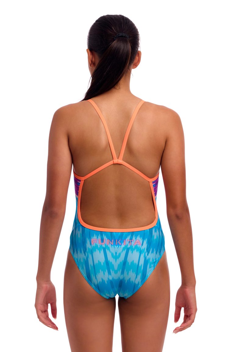 En kvinde ses bagfra iført Funkita Birdie Bird - Single Strap badedragt til piger med blåt og pink mønster, orange stropper, åben ryg og "FUNKITA" trykt på den nederste del af ryggen.
