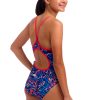 En kvinde med mørkt hår, der er bundet tilbage, smiler og viser bagsiden af sin Funkita Mad Cat - Diamond Back - Piger-badedragt med røde stropper og et farverigt, hvirvlende blåt, rødt og hvidt design på en almindelig hvid baggrund.