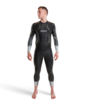 En mand står barfodet på en hvid baggrund iført Zone3 Aspire Våddragt - Herre, en sort våddragt med grå og gule detaljer, og kigger lidt til siden.