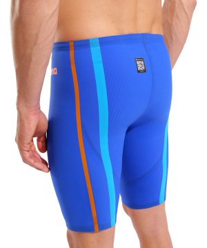En mand, der ses bagfra mod en ensfarvet baggrund, er iført Arena Powerskin Primo Jammer LtD (Neon Blaze) - Herrer: blå racer-badebukser med lyseblå og orange lodrette striber og et lille sort mærke på linningen.